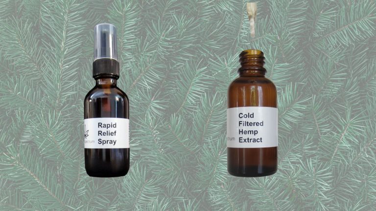 Two bottles of extract on light pine needle background